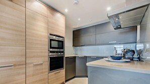 Eine moderne Küche mit Holzschränken, Edelstahlgeräten und einer grauen Arbeitsplatte.