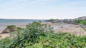 Ein Küstenstrand mit einem Felsen, einer Uferpromenade und Gebäuden entlang des Strandes.
