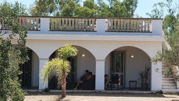 Un edificio con fachada blanca, varios arcos y un balcón con detalles decorativos.