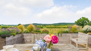 A wooden deck with a table set for tea, surrounded by a wooden fence, overlooking a green landscape. - 1 Bed in Stillington (oc-g0057) (Marton-in-the-Forest)