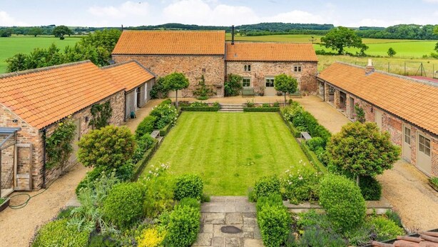A courtyard with a central lawn, surrounded by brick buildings with tiled roofs. - 1 Bed in Stillington (oc-g0057) (Marton-in-the-Forest)