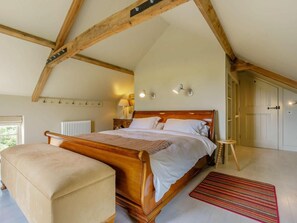 A bedroom with a wooden bed, a bedside table, a lamp, a radiator, and a window. - 1 Bed in Stillington (oc-g0057) (Marton-in-the-Forest)