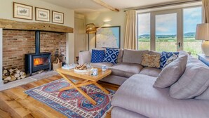 A cozy living room with a fireplace, a sofa, a coffee table, and a view of the countryside. - 1 Bed in Stillington (oc-g0057) (Marton-in-the-Forest)