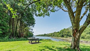 A picnic table by a river with trees and greenery. - 2 Bed in Cosheston (oc-fb059) (Cosheston)