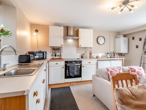 A compact kitchen with a microwave, toaster, and sink. There is a small oven, a clock, and a water heater on the wall. - 2 Bed in Cosheston (oc-fb060) (Cosheston)