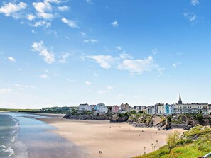 A coastal town with a sandy beach, buildings along the shore, and a prominent church spire. - 2 Bed in Cosheston (oc-fb060) (Cosheston)