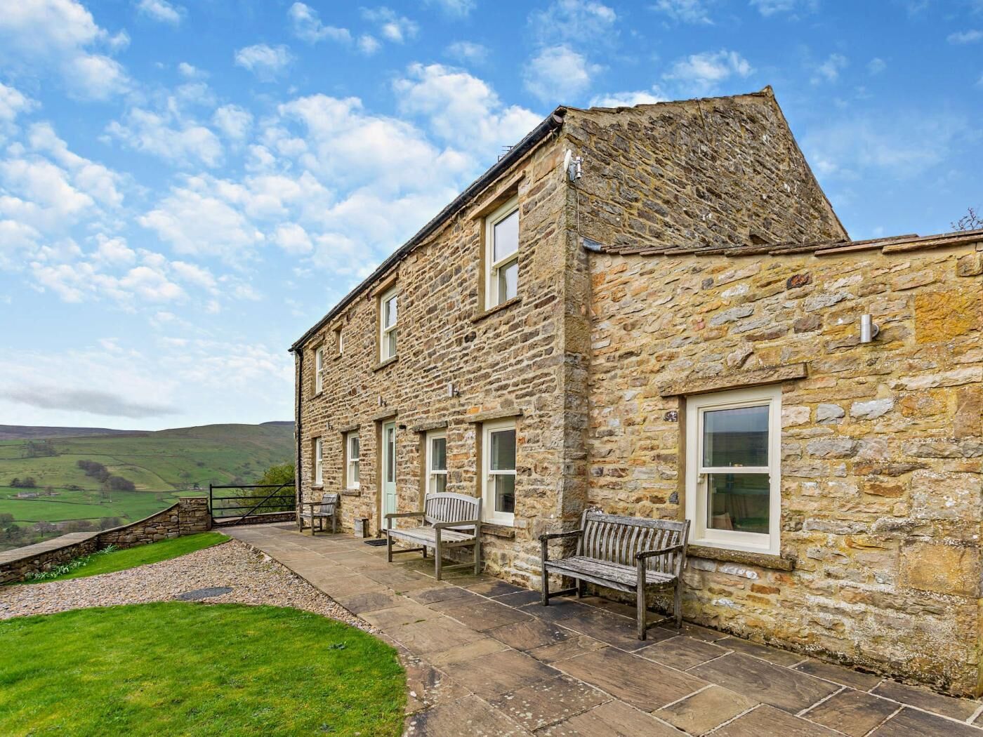 A stone building with a patio area, outdoor seating, and a view of the countryside.