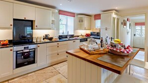 Une cuisine moderne avec des meubles blancs, un îlot central et une vue sur l’extérieur.