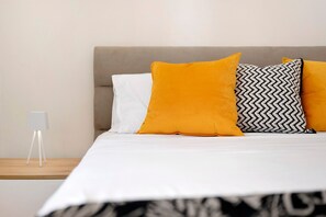 A bed with white bedding and three pillows in different colors and patterns. - Casa Marchesi – Cozy Apartment with Wi-Fi and Air Conditioning (Albenga)