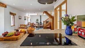 A modern kitchen with a built-in induction cooktop, wooden furniture, and a staircase leading to another level. - 4 Bed in Brecon (oc-82529) (Crai)