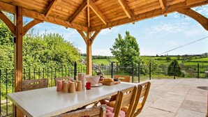 An outdoor wooden pergola with a table and chairs, surrounded by a fenced garden. - 4 Bed in Brecon (oc-82529) (Crai)