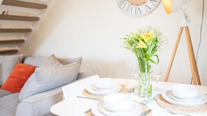 Un coin repas avec une table dressée pour quatre personnes, une horloge et une lampe.