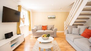 Un salon moderne avec un canapé, une table basse, un téléviseur à écran plat et un escalier.