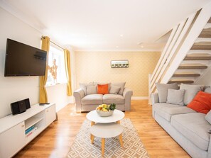 A modern living room with a sofa, a coffee table, a flat-screen TV, and a staircase. - 2 Bed in Bideford (oc-73858) (Westward Ho!)