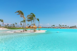 A tropical resort with a clear blue pool, palm trees, and thatched-roof structures. - Encina 29: La Buena Vida! Modern 6-person apartment at Santa Rosalia Resort (Santa Rosalía)