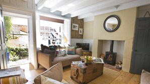 Un salon chaleureux avec un canapé, une commode en bois, une cheminée et un téléviseur.