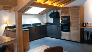 Une cuisine moderne avec des poutres en bois, une lucarne et des appareils électroménagers intégrés.