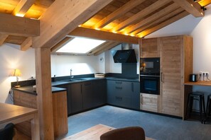 Eine moderne Küche mit Holzbalken, einem Oberlicht und integrierten Geräten.