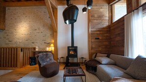 L’intérieur d’un chalet accueillant, avec une cheminée, des murs en bois, un canapé et une table.