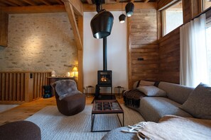 Ein gemütliches Blockhaus-Interieur mit Kamin, Holzwänden, einer Couch und einem Tisch.