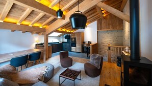 Un intérieur chaleureux avec un plafond en bois, un coin repas, une cuisine et une cheminée.