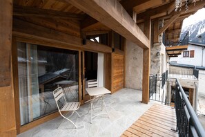 A wooden balcony with a table and chairs, stone flooring, and a view of mountains. - Chalet Olia – Cozy (Peisey-Nancroix)