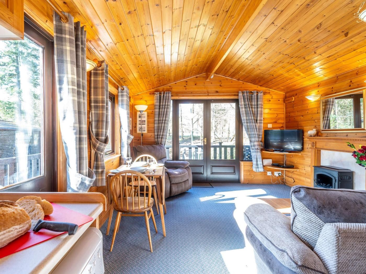 A cozy cabin interior with a dining area, sofa, fireplace, and a television.