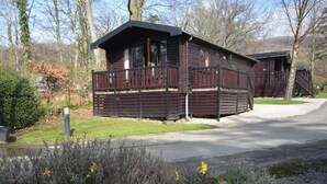 Eine Holzhütte mit einem Balkon, umgeben von einer Schotterauffahrt und einem Garten mit Narzissen.