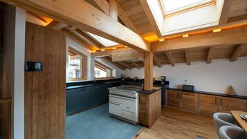 A modern kitchen with wooden beams, a stove, and a dining area with a table and chairs.