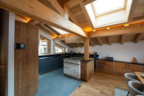 Eine moderne Küche mit Holzbalken, einem Herd und einem Essbereich mit Tisch und Stühlen.