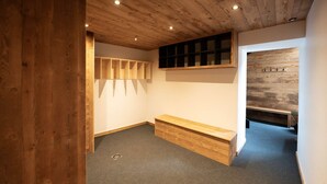 Een kamer met houten plafond, een bankje, een wandplank en een houten wandpaneel.