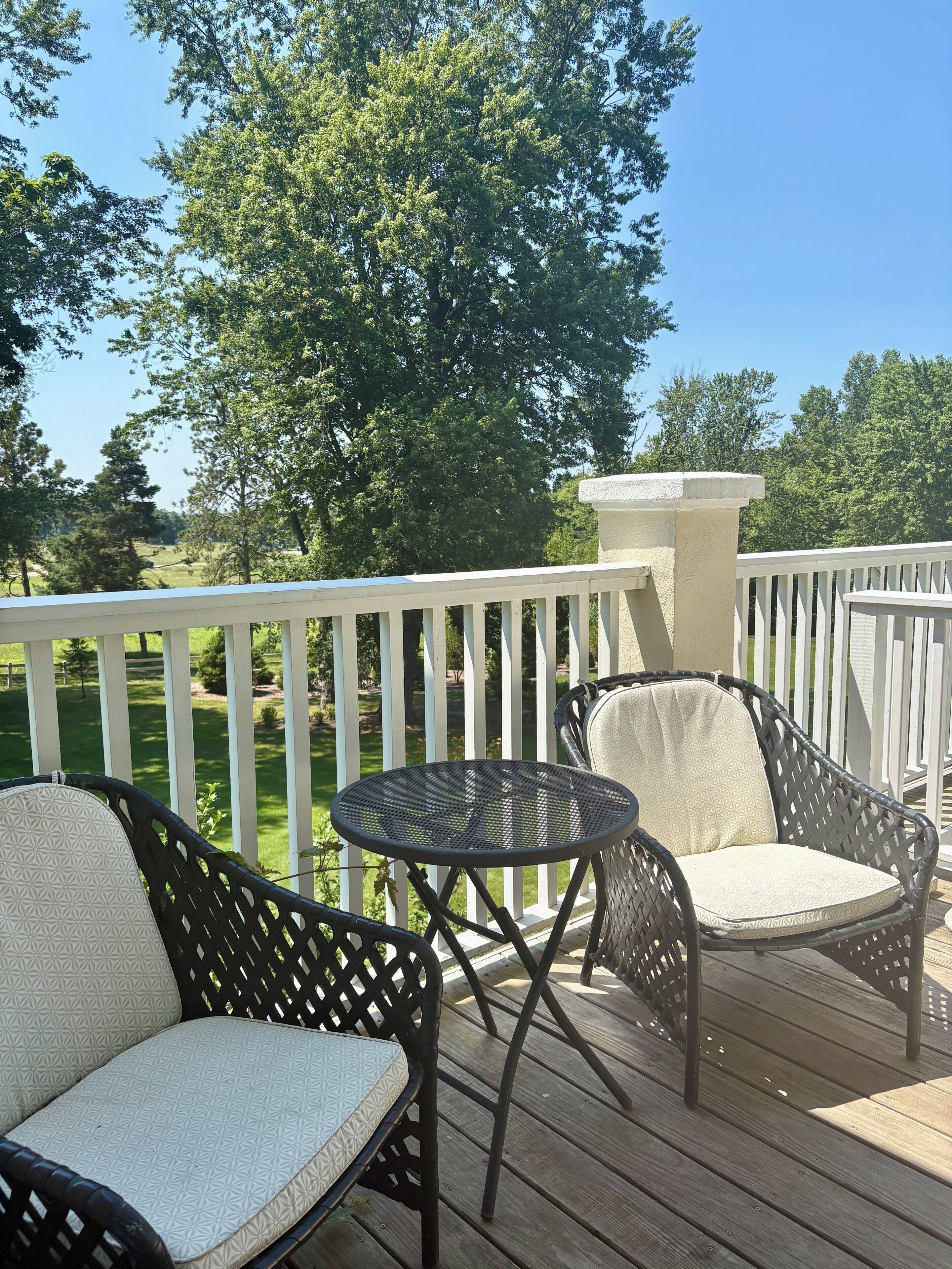 A wooden deck with wicker furniture and a white railing.