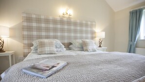 A neatly made bed with a plaid headboard, two bedside lamps, and a magazine on the bed. - 2 Bed in Howden (oc-g0104) (Saltmarshe)