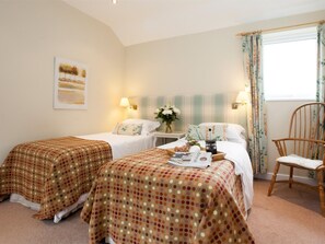 A hotel room with two beds, a chair, a bedside table with a lamp, a window with curtains, and a painting on the wall. - 2 Bed in Howden (oc-g0104) (Saltmarshe)