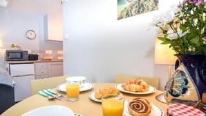Una colazione con piatti di cibo, una ciotola, un bicchiere di succo d'arancia e un vaso con fiori.
