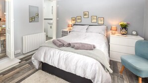 Una camera da letto con un letto, comodini, una sedia e un termosifone.