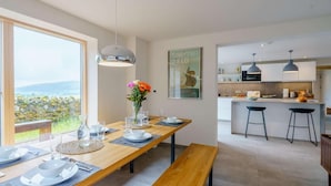 A modern kitchen with pendant lights, a dining area with a wooden table set for two, and a view of the outdoors. - 3 Bed in Matterdale (oc-83002) (Ullswater)