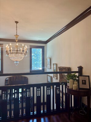 A room with a chandelier, framed pictures, and a window with a view.