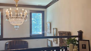 A room with a chandelier, framed pictures, and a window with a view.