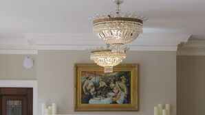 Ein Esszimmer mit einer Chandelüstere, einem Kamin und einem Gemälde an der Wand.