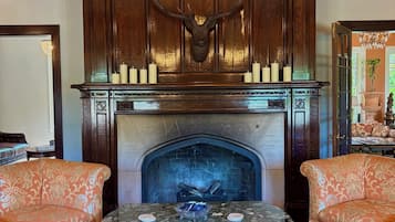 A fireplace with a deer head, surrounded by ornate wood paneling and a chandelier.