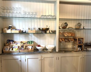 A kitchen with glass shelves holding various items like glassware, coffee makers, and food packaging. - Third floor dormer style room with queen bed, reading nook, private bath with shower,  and property views, located in the Belvedere Estate in Saugatuck (Saugatuck)