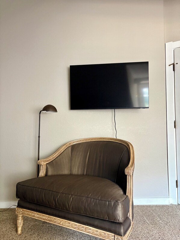 Ein Zimmer mit einer Couch, einem flachbildfernseher an der Wand und einer Lampe.