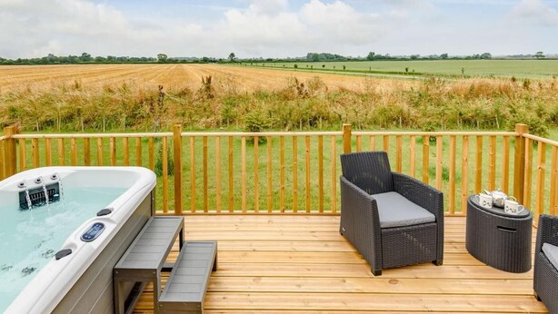 A wooden deck with a hot tub, wicker furniture, and a view of a field. - 1 Bed in Market Rasen (oc-83846) (Faldingworth)