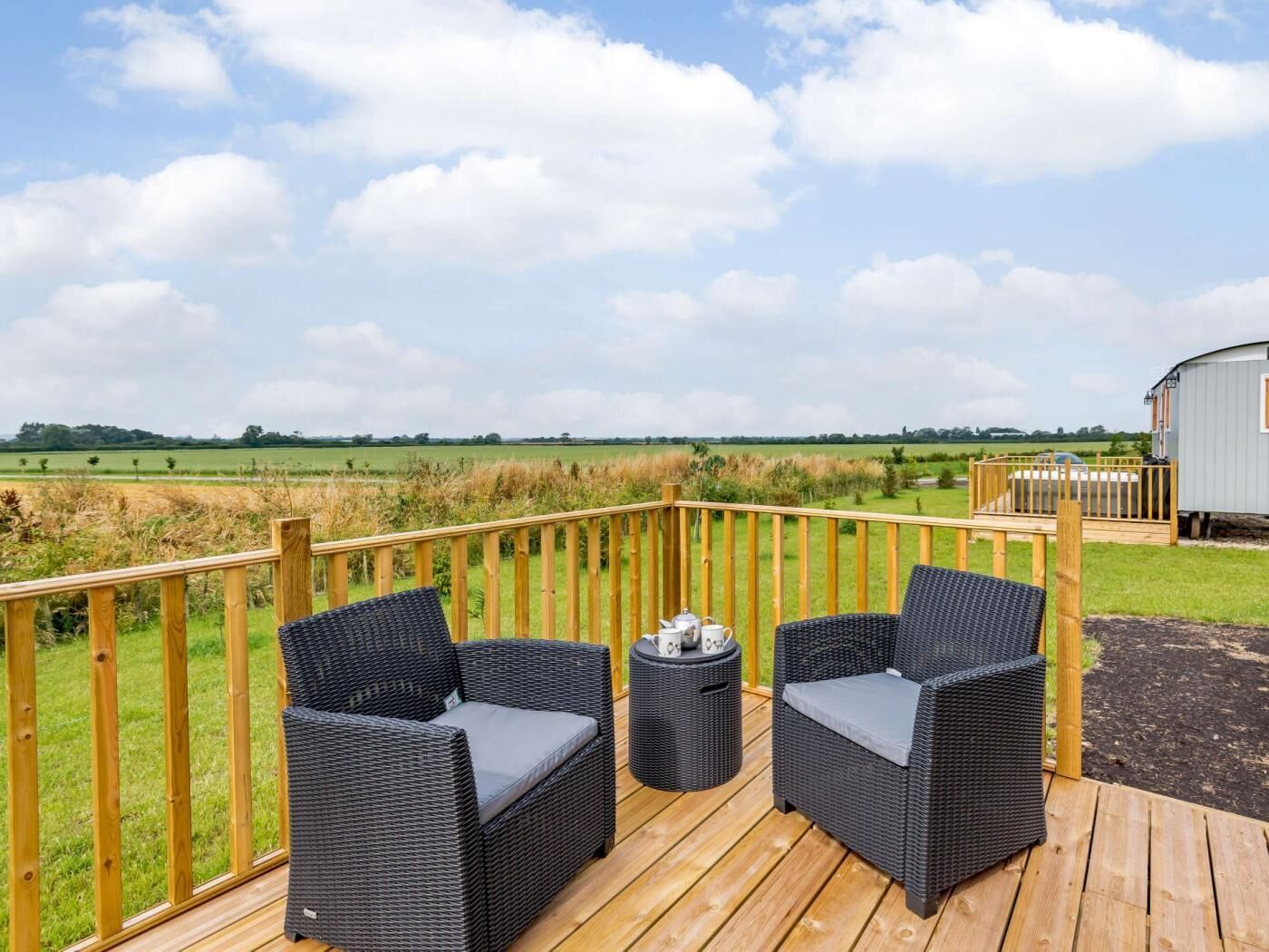Een terras met rieten meubels en uitzicht op een veld.