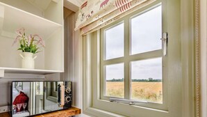 A kitchen with a microwave, a shelf with a vase of flowers, and a window with a view of a field. - 1 Bed in Market Rasen (oc-83846) (Faldingworth)