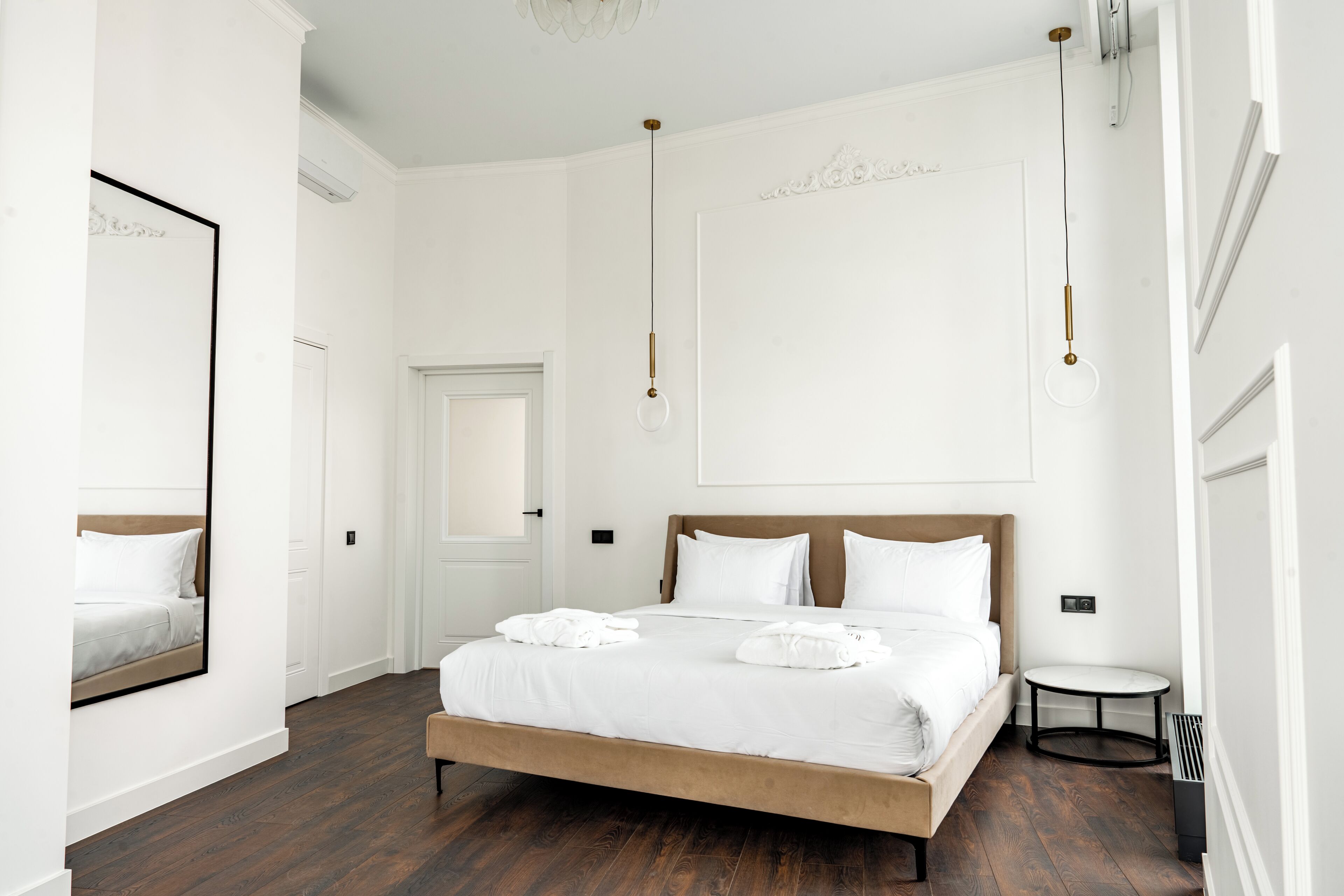 A hotel room with a large bed, a round table, and a mirror.