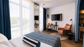 Ein Hotelzimmer mit Bett, Schreibtisch, Stuhl, Fernseher und einer Küchenzeile.