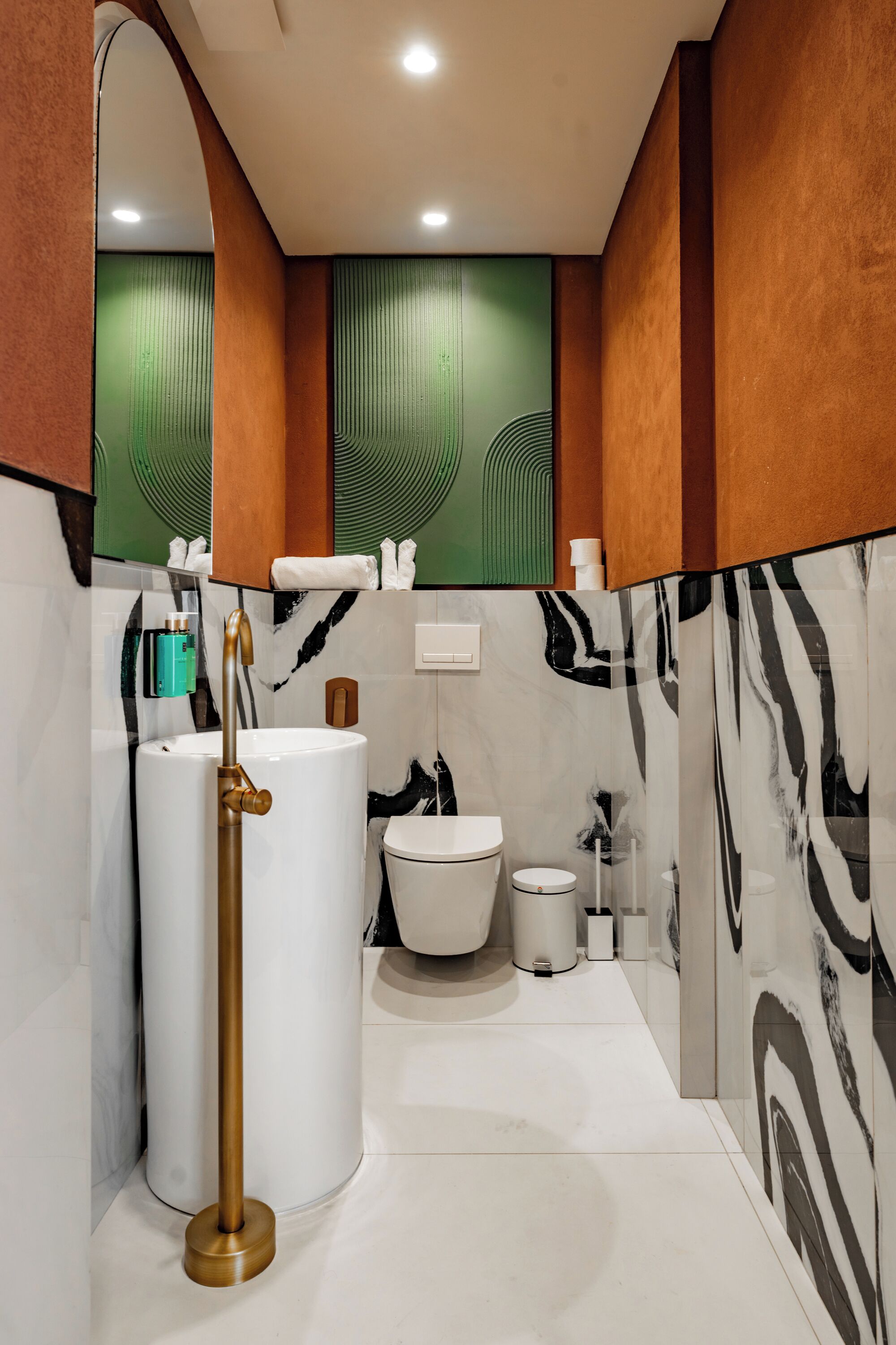 A modern bathroom with a large white sink, a gold faucet, a white toilet, and a bidet.