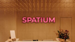 A reception desk with a sign that reads 'SPATIUM' and a floral arrangement on the right.
